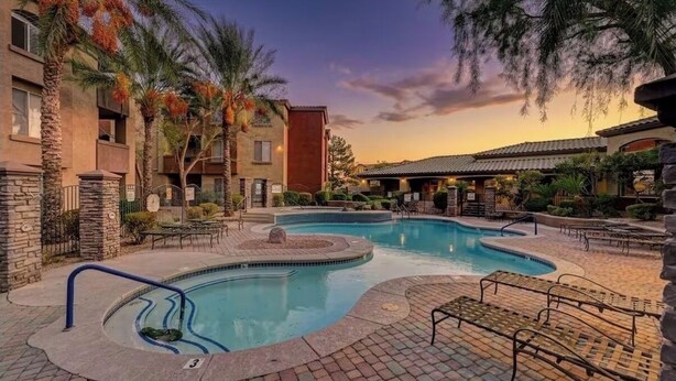Un hotel con piscina, palmeras y un atardecer.