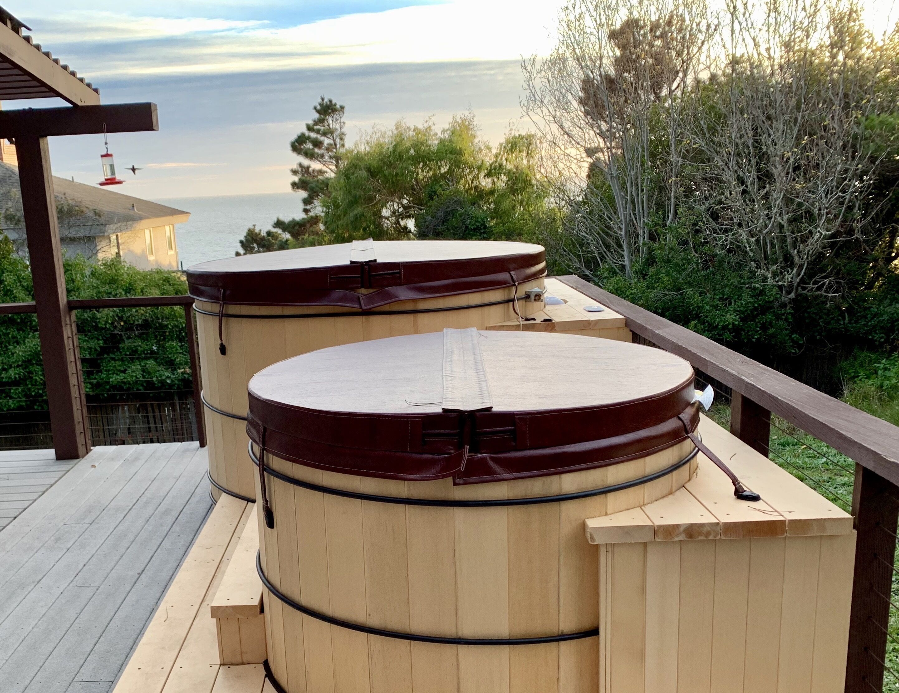 Two wooden barrels on a deck with a view of the sea.