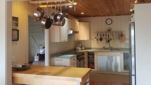 Una cocina con un cartel que dice 'WELCOME', techo de madera, electrodomésticos de acero inoxidable y ollas colgantes.