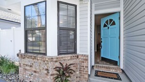 A house with a blue door, a brick exterior, and a potted plant.