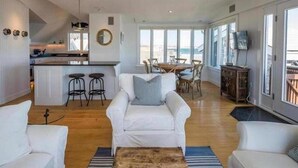 Un salón amplio con un sofá blanco, una mesa de centro de madera y una zona de comedor con mesa y sillas.