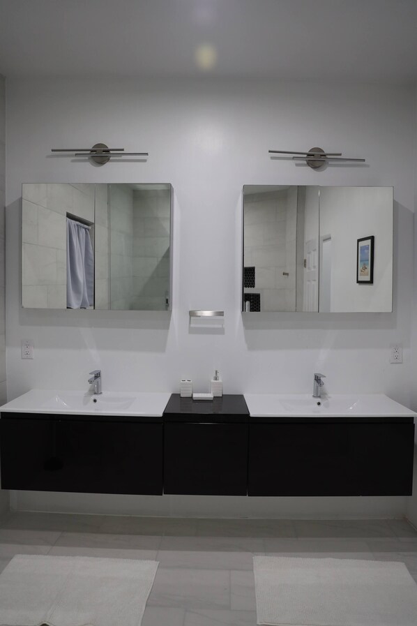 Un baño moderno con dos lavamanos, un espejo grande y un tocador negro.