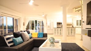 A living room with a sofa, coffee table, and a view of the kitchen. - Escape to Exhale at a modern style villa with breathtaking views of chalk sound (Providenciales)