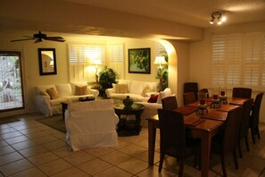 A living room with a dining area, featuring a sofa set, a coffee table, and a dining table with chairs. - Clearwater Beach Pool House Rental - Just Steps to the Beach (Clearwater Beach)