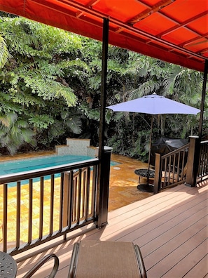 A wooden deck with a pool, surrounded by lush greenery. - Clearwater Beach Pool House Rental - Just Steps to the Beach (Clearwater Beach)