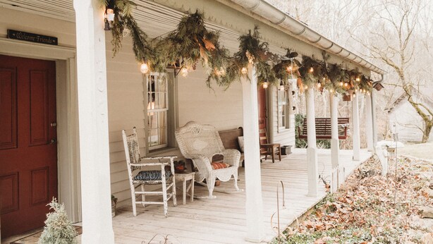 A porch with a white door, a wicker chair, and a bench.