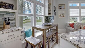 Une cuisine avec une table en bois, un banc et un plan de travail muni d’un porte-couteaux.