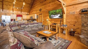 Interior acogedor de una cabaña de troncos con sala de estar, cocina y comedor.