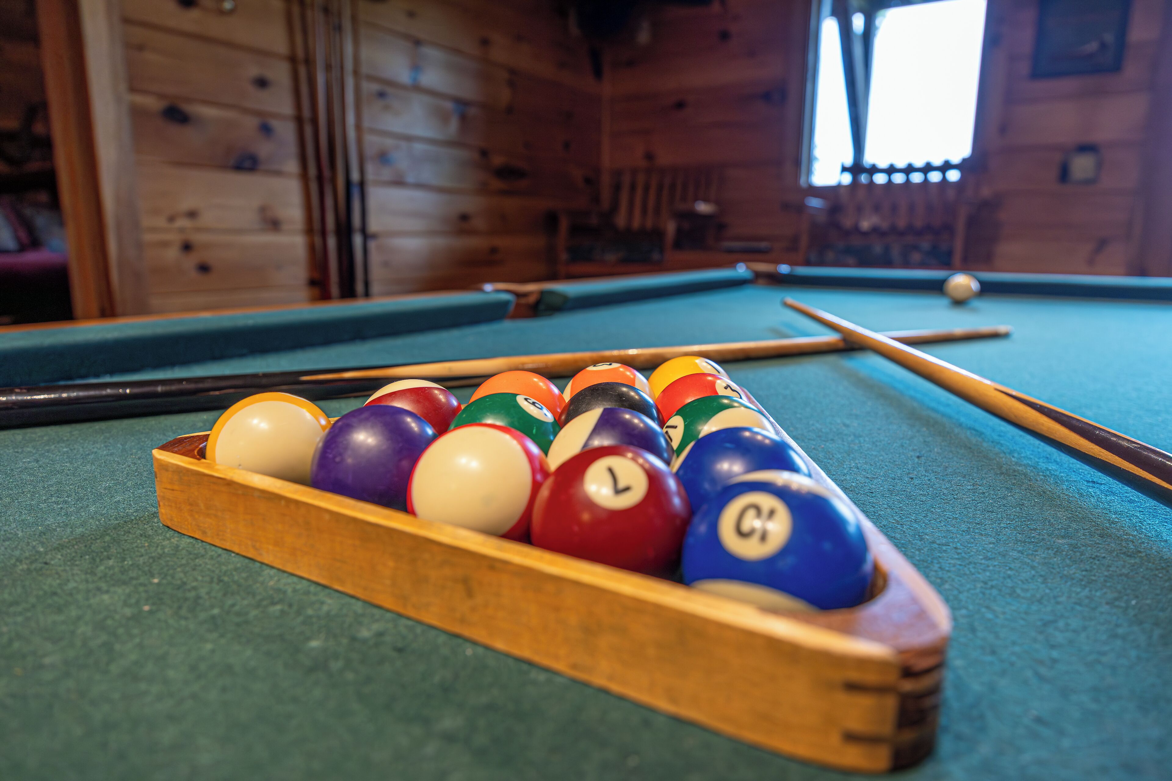 Une table de billard avec un porte-billes en bois contenant les billes.