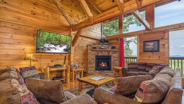 Interior acogedor de una cabaña con chimenea, paredes de madera, un televisor y asientos cómodos.