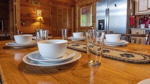 Un interior de madera con una mesa de comedor dispuesta para cuatro, incluyendo cuencos, platos y vasos.