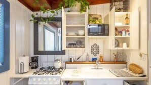 A compact kitchen with white cabinetry, a gas stove, a microwave, and a small countertop area.