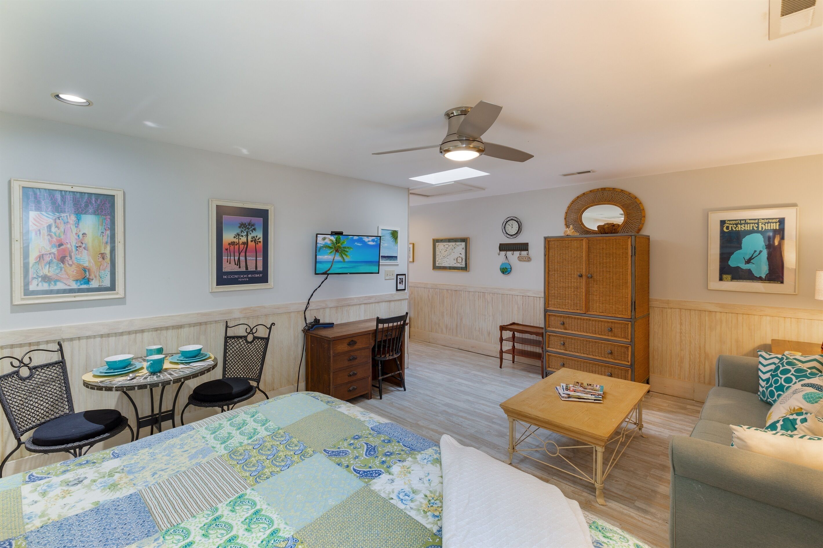 Una habitación acogedora con cama, escritorio, silla, sofá y televisor.