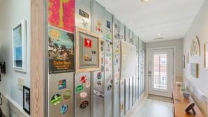 A hallway with a wooden floor, a door with a window, and a wall covered with various stickers and posters.