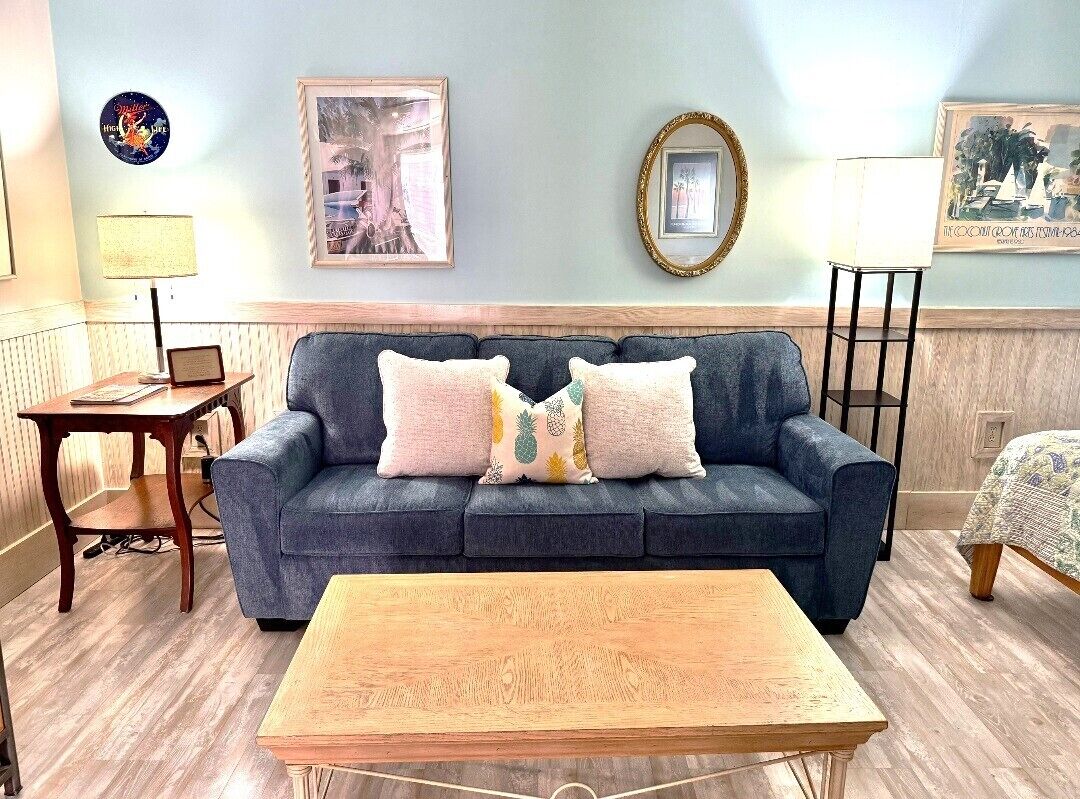 A living room with a sofa, a coffee table, a lamp, and framed pictures on the wall.