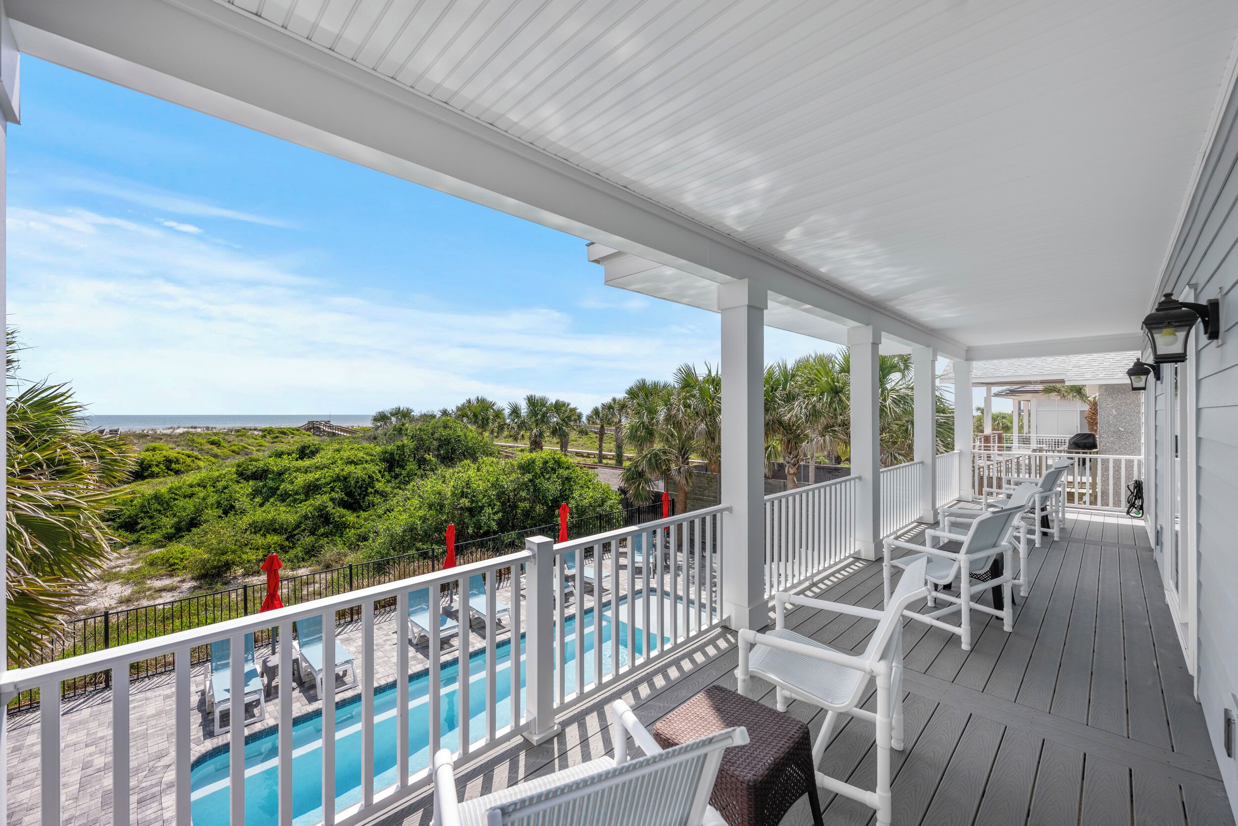 Un espace extérieur abrité, doté d’une piscine, de mobilier blanc et offrant une vue sur l’océan.