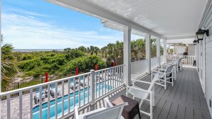 Ein überdachter Außenbereich mit Pool, weißen Möbeln und Meerblick.
