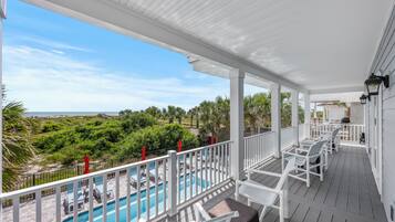 Un espace extérieur abrité, doté d’une piscine, de mobilier blanc et offrant une vue sur l’océan.