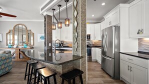 A modern kitchen with a central island, stainless steel appliances, and a stone accent wall. - 🏖️ 5 Bedroom Penthouse Ocean Views, Renovated, Pool, Stunning Ocean Views🏖️ (Ocean City)