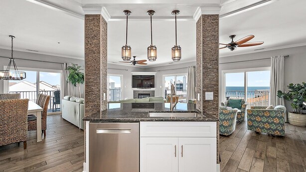 A spacious living area with a large island, stone accent walls, and a ceiling fan. - 🏖️ 5 Bedroom Penthouse Ocean Views, Renovated, Pool, Stunning Ocean Views🏖️ (Ocean City)