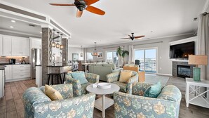 A spacious living area with a large sofa set, a dining table, and a kitchen with white cabinets. - 🏖️ 5 Bedroom Penthouse Ocean Views, Renovated, Pool, Stunning Ocean Views🏖️ (Ocean City)