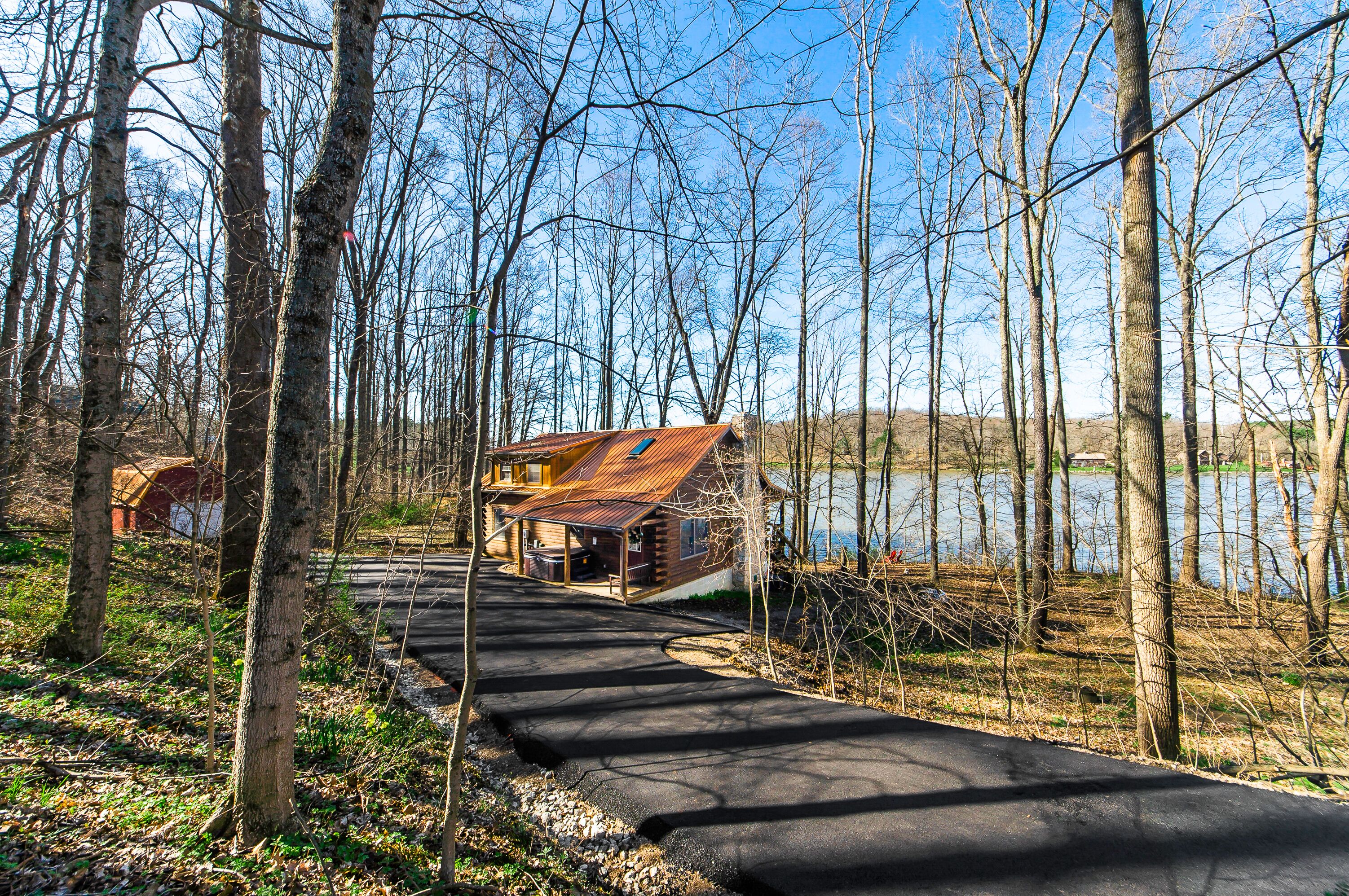 Une cabane avec un toit en métal et une jetée qui s’avance dans un lac, le tout entouré d’arbres.