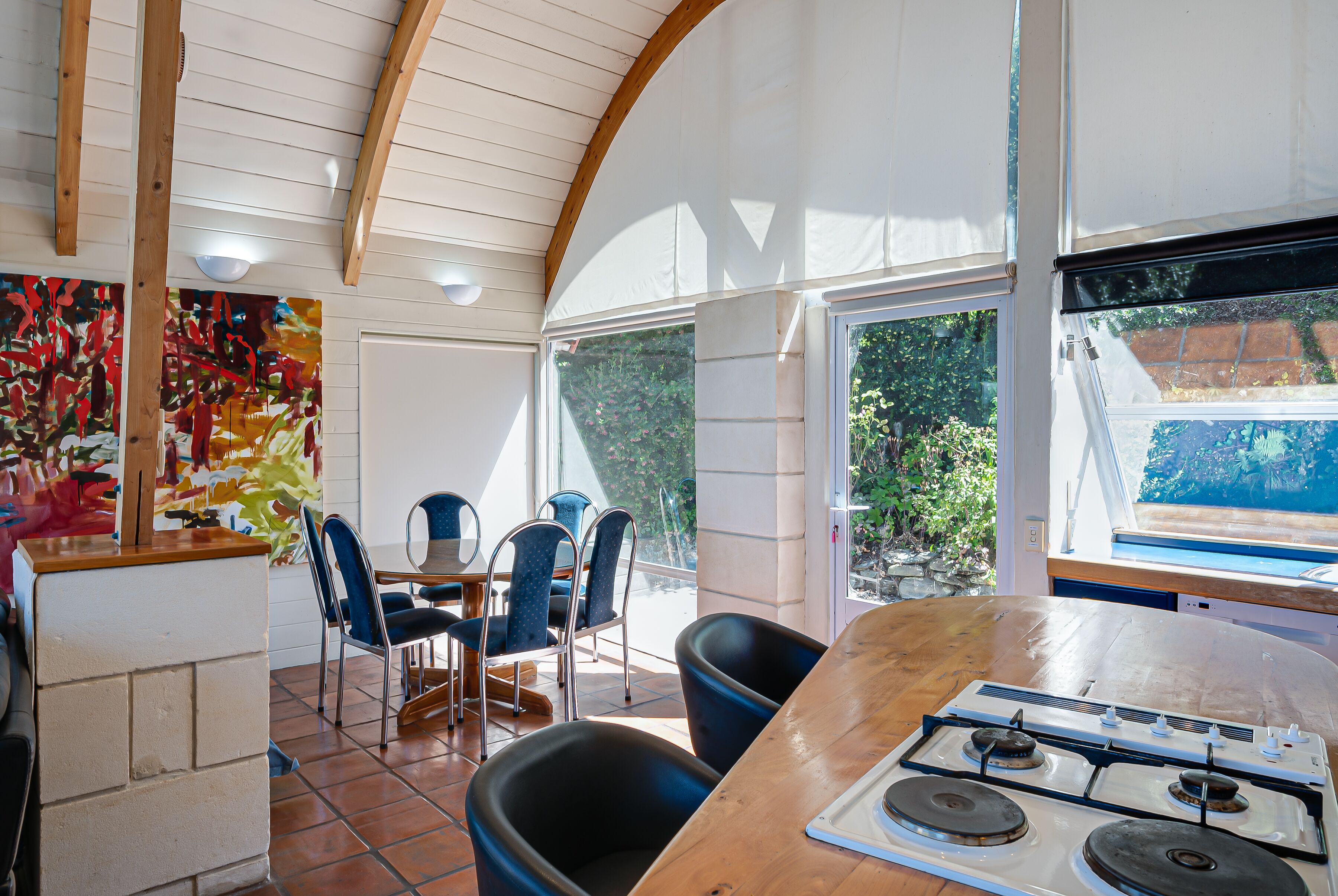 A kitchen with a stove, chairs, and a dining table.