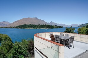 A terrace with a table and chairs overlooking a lake and mountains. - Lakefront Vacation Home (Queenstown)