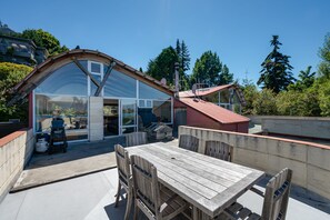 A modern house with a large glass window, a wooden deck, and a red roof. - Lakefront Vacation Home (Queenstown)