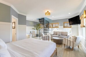 A modern bedroom with a large bed, a spiral staircase, a sofa, and a TV. - 4 Balconies, Water Views, Fireplace, Kitchen - Great For Groups (Newport)