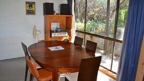 Una sala de conferències amb taula i cadires de fusta, un jukebox antic i un ventilador.