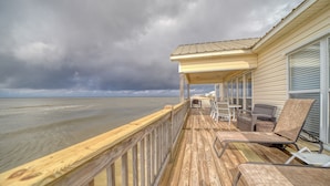 Um deck de madeira com móveis de exterior, com vista para uma praia.
