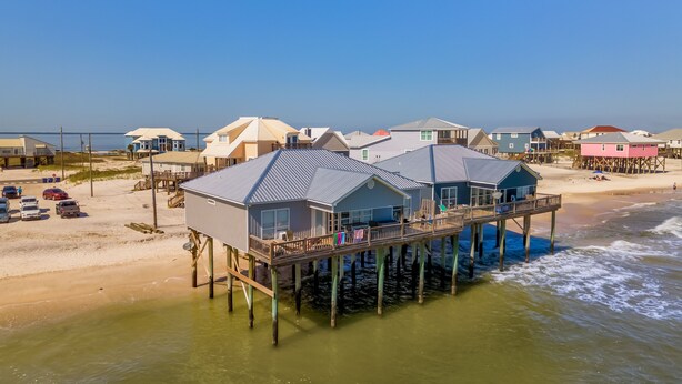 Uma propriedade à beira-mar com várias casas sobre pilares na água, com grandes janelas e varandas.