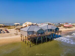 A beachfront property with multiple houses on stilts over the water, featuring large windows and balconies.