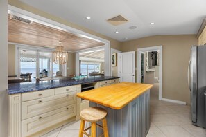 A kitchen with a wooden island, white cabinetry, and a view to the outside. - Private Cable Beach villa with pool, oceanfront terrace & guest cottage (Cable Beach, Nassau)
