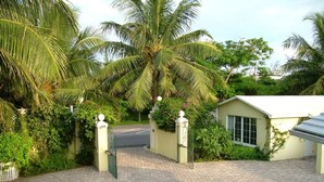 A paved driveway leading to a gated entrance with a small building. - Luxury Beach--front house, perfect location! Cable Beach BEAUT! Walk to Baha Mar (Cable Beach, Nassau)