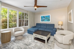 A living room with a sectional sofa, two armchairs, a coffee table, a ceiling fan, a window with curtains, a painting, and a lamp. - Private Cable Beach villa with pool, oceanfront terrace & guest cottage (Cable Beach, Nassau)