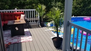Eine Terrasse mit Pool, rotem Gartenmöbel und Topfpflanzen.