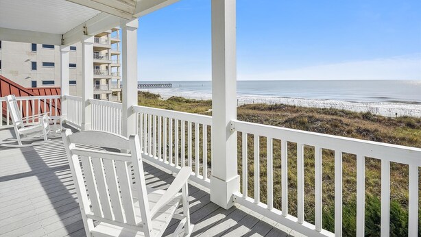 A wooden deck with white railings overlooking a beach and a pier. - One Happy Place, Luxury Oceanfront House in Cherry Grove, Pool and Spa (North Myrtle Beach)