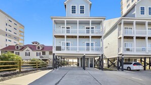 A beachfront hotel with multiple balconies, a covered walkway, and a parking area. - One Happy Place, Luxury Oceanfront House in Cherry Grove, Pool and Spa (North Myrtle Beach)