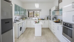 Een moderne keuken met witte kasten, roestvrijstalen apparatuur en een centraal eiland.