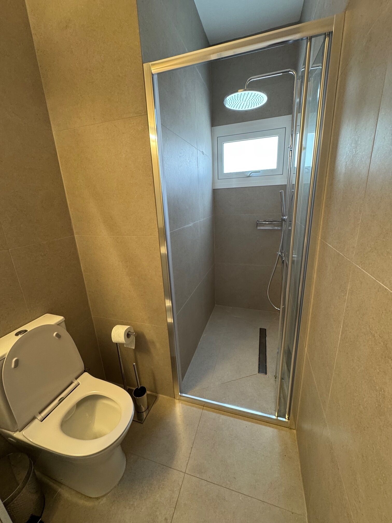 Une salle de bain comprenant des toilettes, un espace douche et une fenêtre.