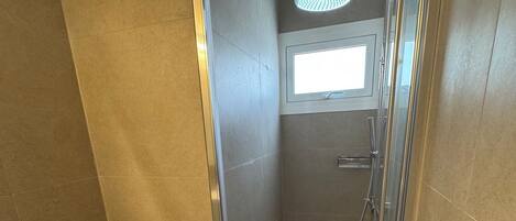 Une salle de bain comprenant des toilettes, un espace douche et une fenêtre.