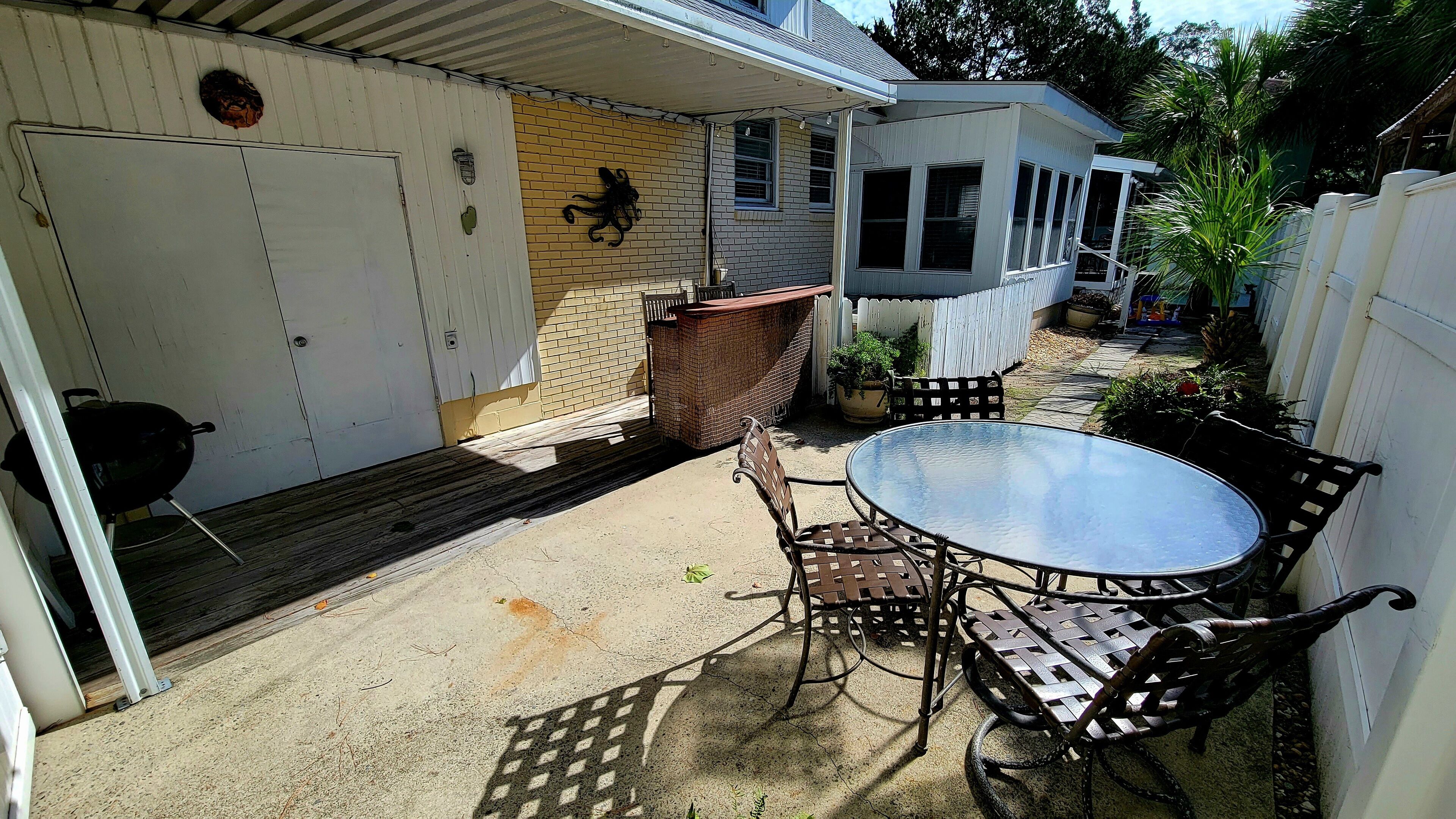 Un patio couvert avec une table et des chaises, un barbecue et un mur en briques.