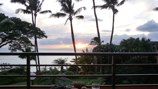 A table set for two with a sunset view, a fruit bowl, and two glasses of water.