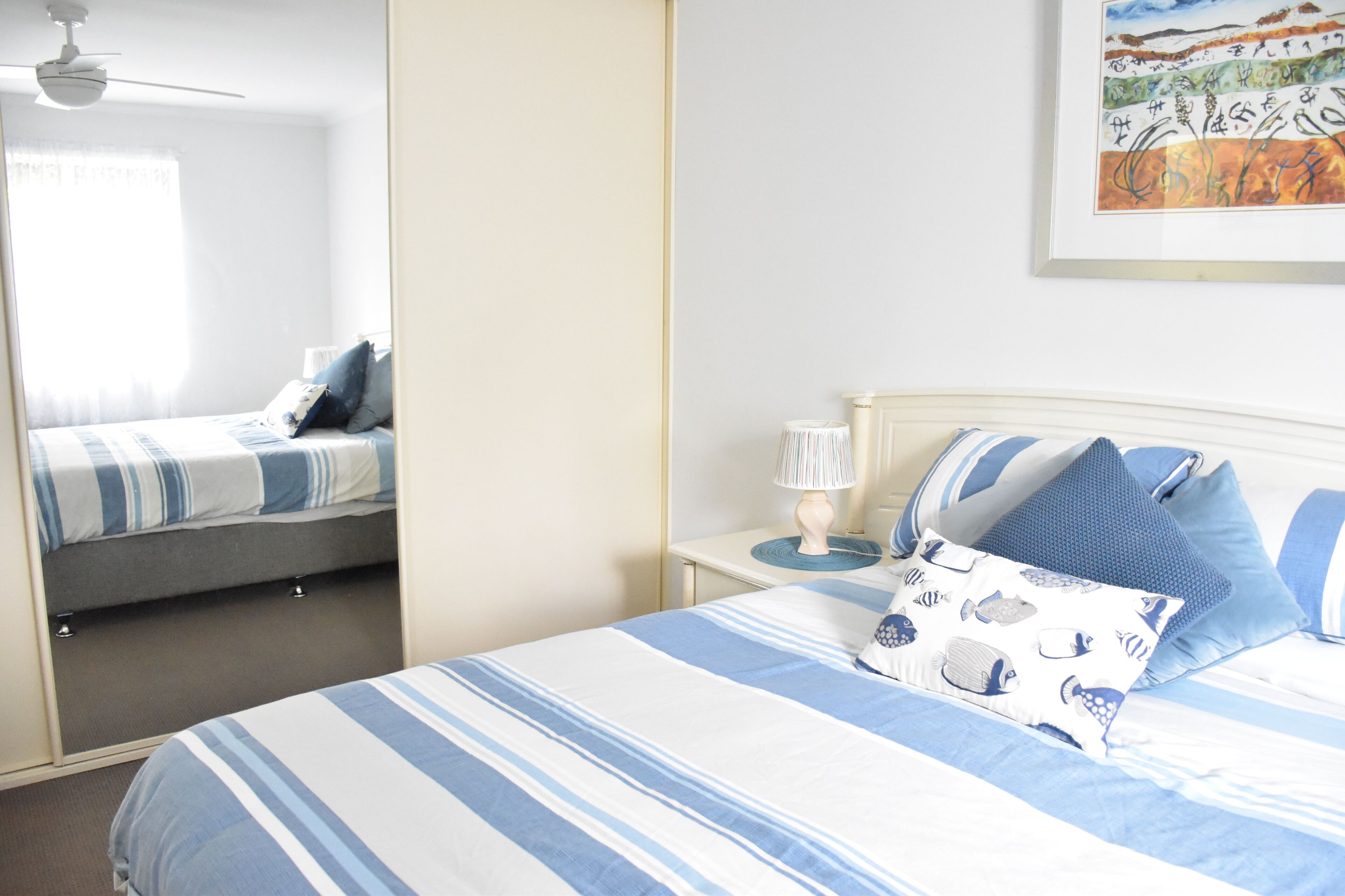 A bedroom with a bed, a nightstand, a lamp, and a ceiling fan.