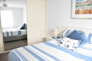 Une chambre à coucher avec un lit, une table de chevet, une lampe et un ventilateur de plafond.