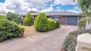 A residential property with a paved driveway, neatly trimmed hedges, and a garage.