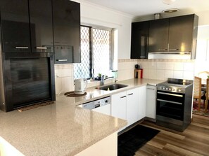 A modern kitchen with dark cabinets, a stainless steel range, and a dishwasher.
