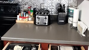 Een keuken met houten kastjes, een fornuis en diverse keukengerei en apparaten.